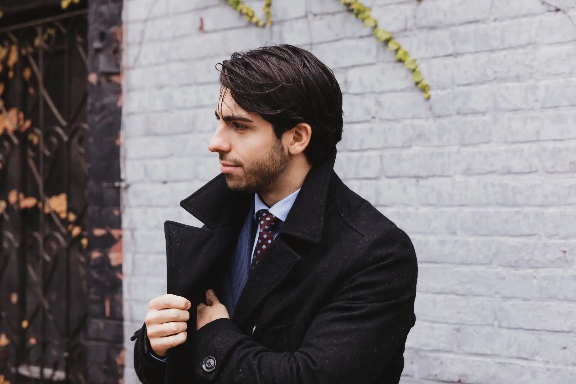 Black wool overcoat with a notched collar and buttoned cuffs.